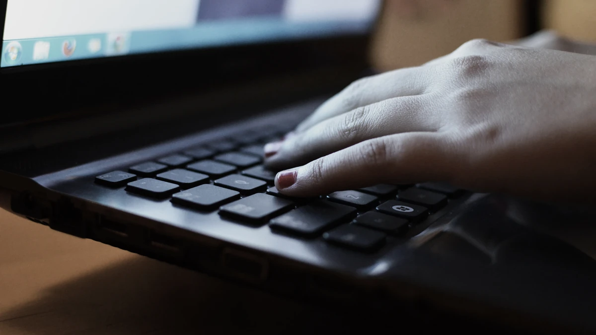 Hand resting on the keys of a dark laptop keyboard