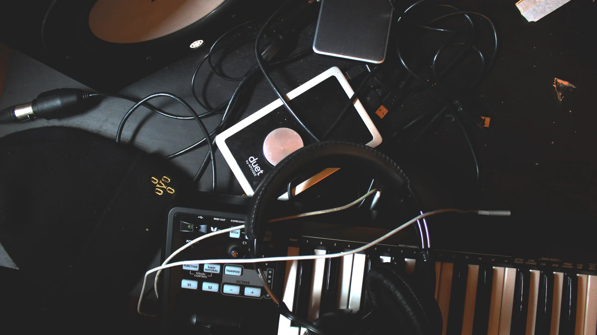 Overhead view of a Roland keyboard, headphones and cables on a dark desk