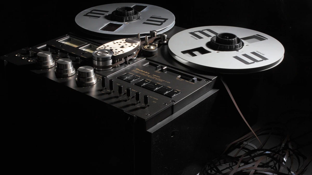 Reel-to-reel tape deck with two silver reels on a dark background
